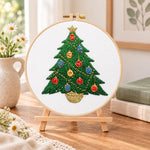Colourful christmas tree embroidery kit finished hoop displayed on a wooden stand as cozy tabletop decor