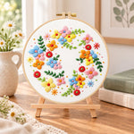 Colourful floral wreath embroidery kit finished hoop displayed on a wooden stand as cosy tabletop decor