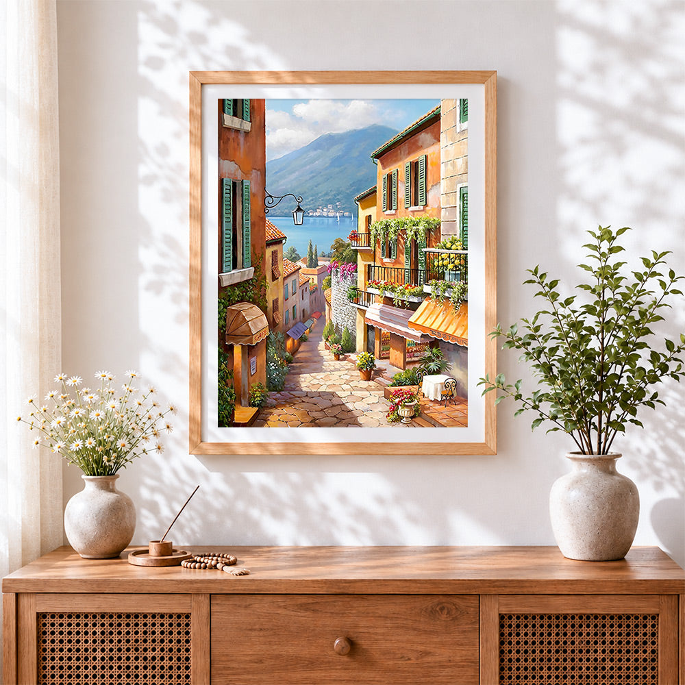 Finished colourful hillside village and café cross stitch artwork displayed