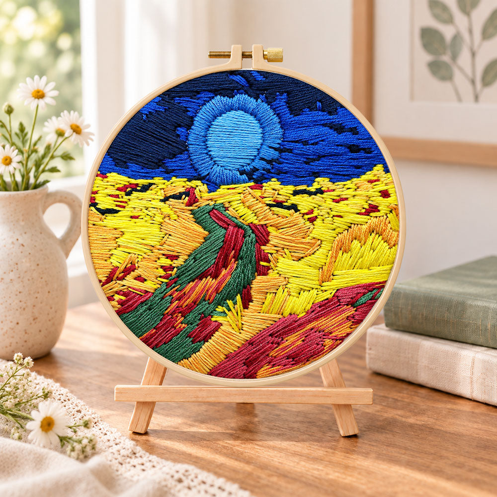 Colourful mountain sunset embroidery kit finished hoop displayed on a wooden stand as cozy tabletop decor