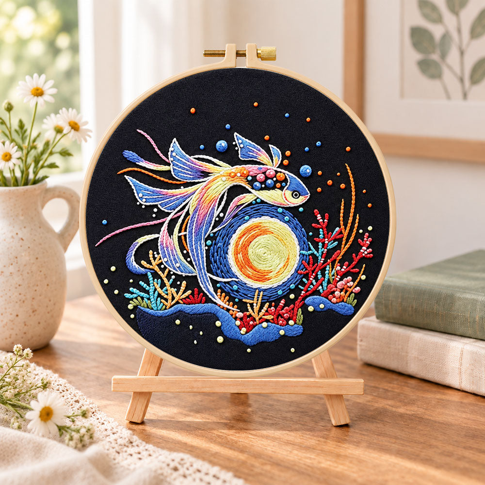 Cosmic betta fish embroidery kit finished hoop displayed on a wooden stand as cosy tabletop decor