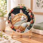 Cosy napping orange cat embroidery kit finished hoop displayed on a wooden stand as cosy tabletop decor
