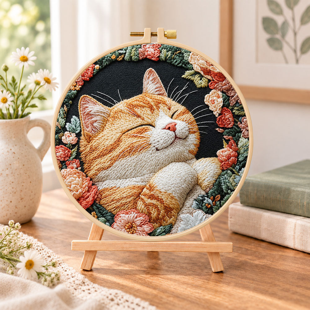 Cosy napping orange cat embroidery kit finished hoop displayed on a wooden stand as cosy tabletop decor