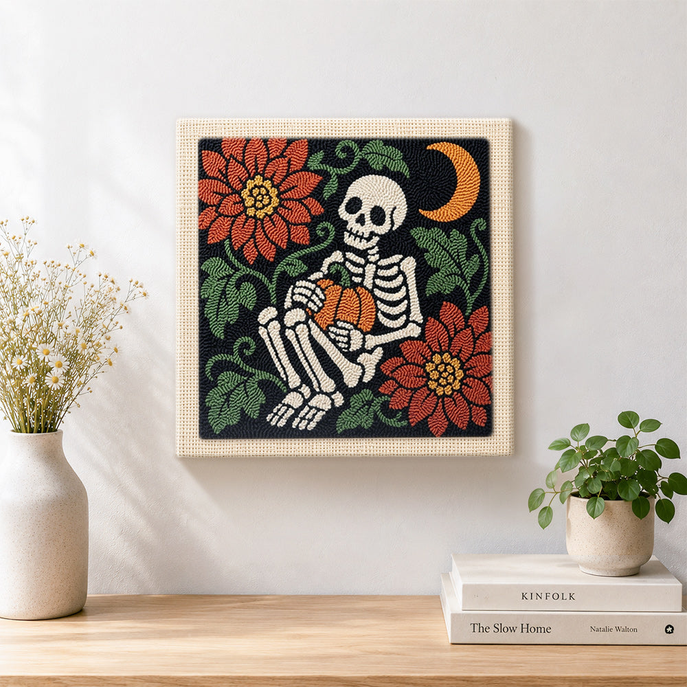 Finished cosy skeleton holding pumpkin artwork displayed on a wall