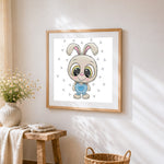 Cute cartoon bunny in dungarees cross stitch artwork displayed on wall as home decor