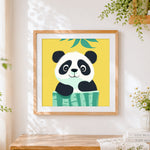 Finished cute cartoon panda peeking over bamboo cross stitch artwork displayed