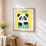 Cute cartoon panda peeking over bamboo cross stitch artwork displayed on wall as home decor
