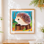 Finished cute hedgehog on a tree stump cross stitch artwork displayed
