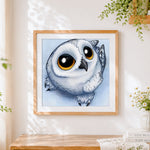 Finished cute round snowy owl cross stitch artwork displayed
