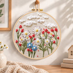 Daisy garden with clouds embroidery kit finished hoop displayed on a wooden stand as cosy tabletop decor