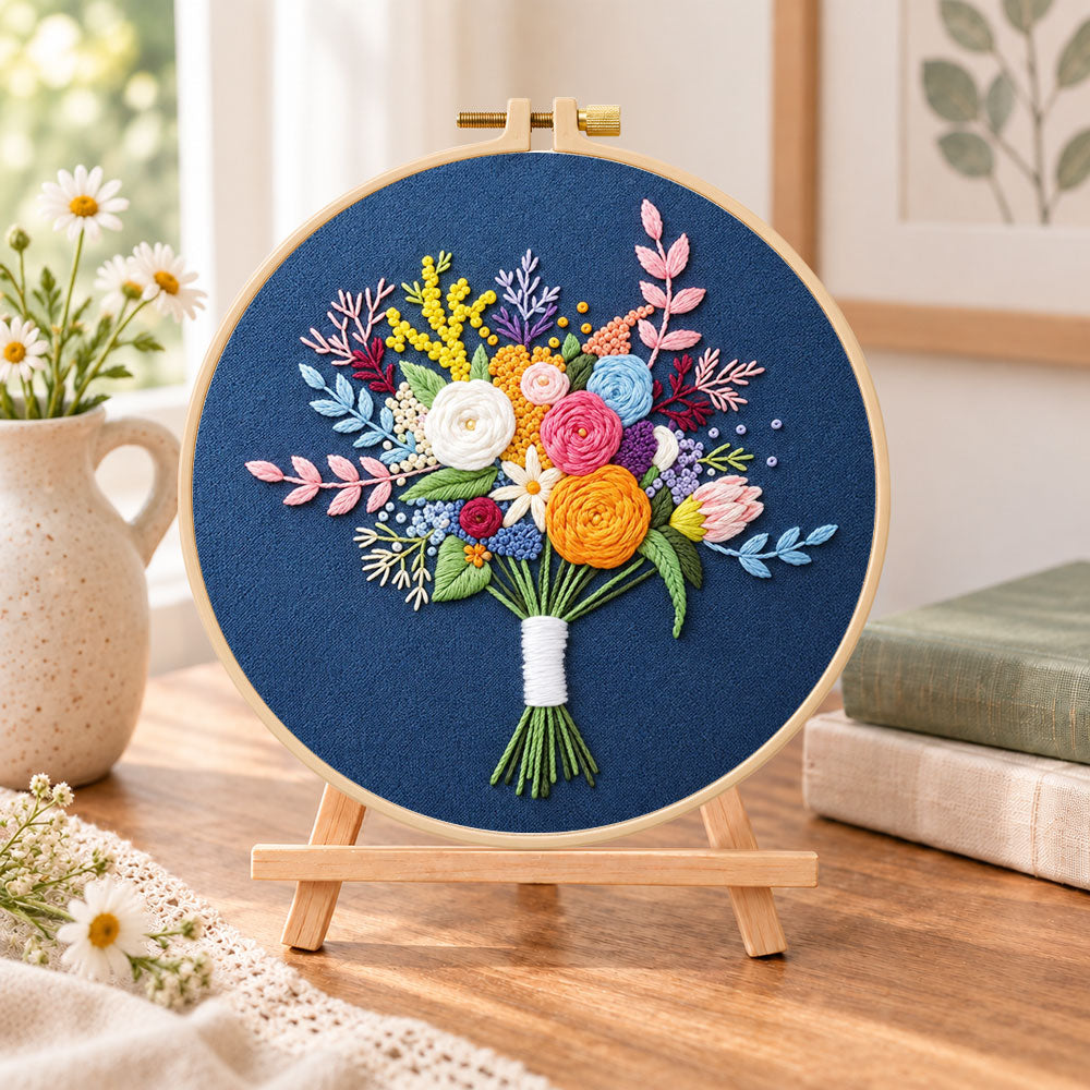 Deep blue mixed flower bouquet embroidery kit finished hoop displayed on a wooden stand as cosy tabletop decor