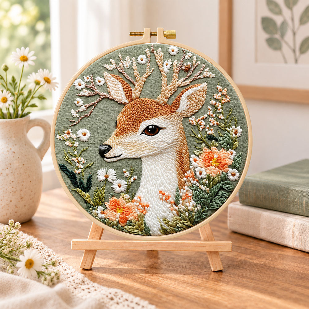 Deer and wild daisies embroidery kit finished hoop displayed on a wooden stand as cosy tabletop decor