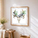 Deer skull with blue floral crown cross stitch artwork displayed on wall as home decor