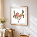 Deer skull with pink flowers cross stitch artwork displayed on wall as home decor