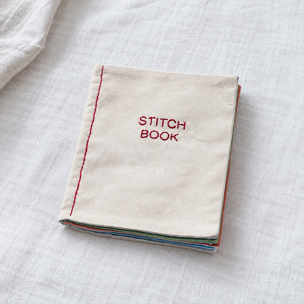 Closed DIY embroidery stitch practice book with an embroidered fabric cover and layered fabric pages
