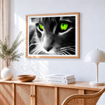 Dramatic cat with neon green eyes cross stitch artwork displayed on wall as home decor