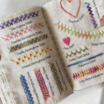 Open embroidery stitch book showing different hand embroidery stitch samples and practice pages.