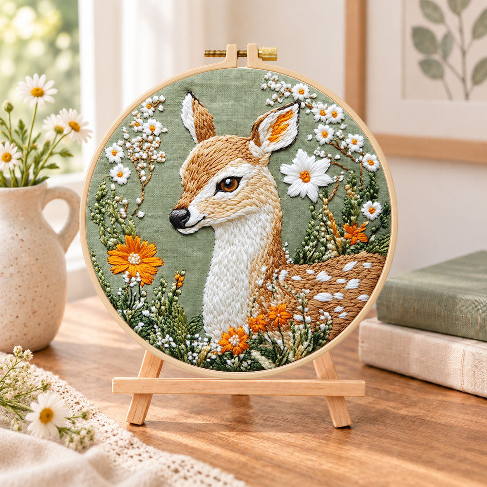 Fawn with daisies and orange blooms embroidery kit finished hoop displayed on a wooden stand as cosy tabletop decor