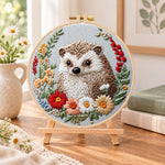 Floral framed hedgehog embroidery kit finished hoop displayed on a wooden stand as cozy tabletop decor