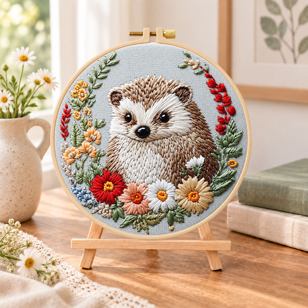Floral framed hedgehog embroidery kit finished hoop displayed on a wooden stand as cozy tabletop decor