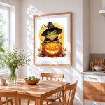 Frog in witch hat with pumpkin cross stitch artwork displayed on wall as home decor
