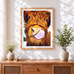 Finished funny highland cow licking lips cross stitch artwork displayed