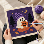 Creating handmade ghost holding pumpkin punch needle artwork