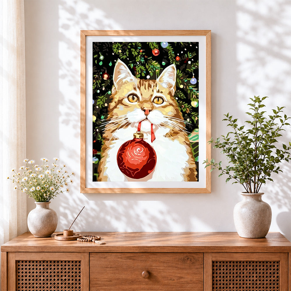 Finished ginger cat holding a red bauble cross stitch artwork displayed