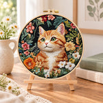 Ginger cat in wild blooms embroidery kit finished hoop displayed on a wooden stand as cozy tabletop decor