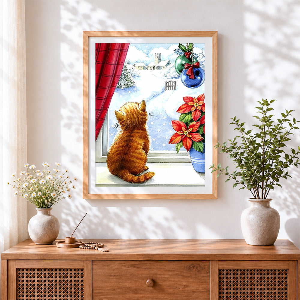 Finished ginger cat looking at a snowy church cross stitch artwork displayed