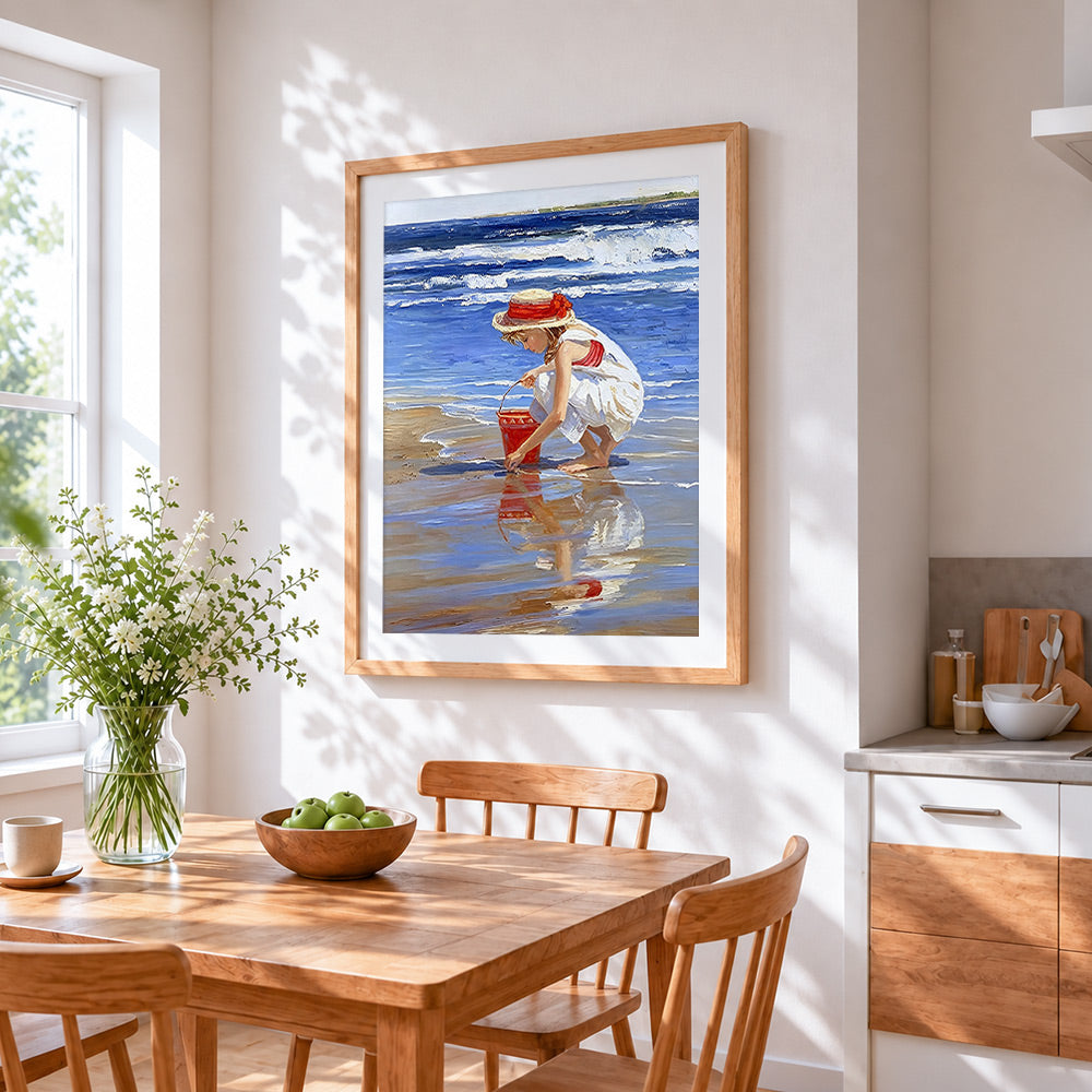 Girl on beach with red bucket cross stitch artwork displayed on wall as home decor