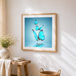 Glowing blue butterflies over water cross stitch artwork displayed on wall as home decor
