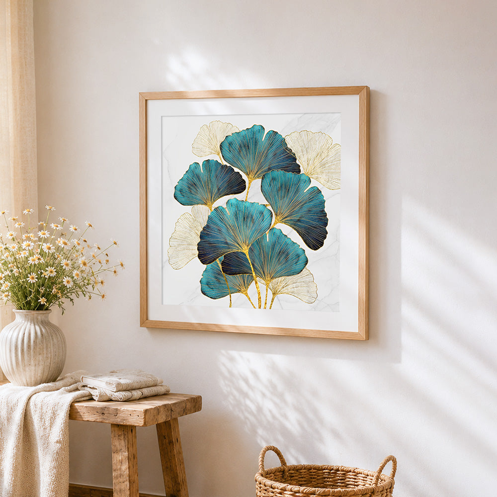 Gold and teal ginkgo leaves on marble cross stitch artwork displayed on wall as home decor