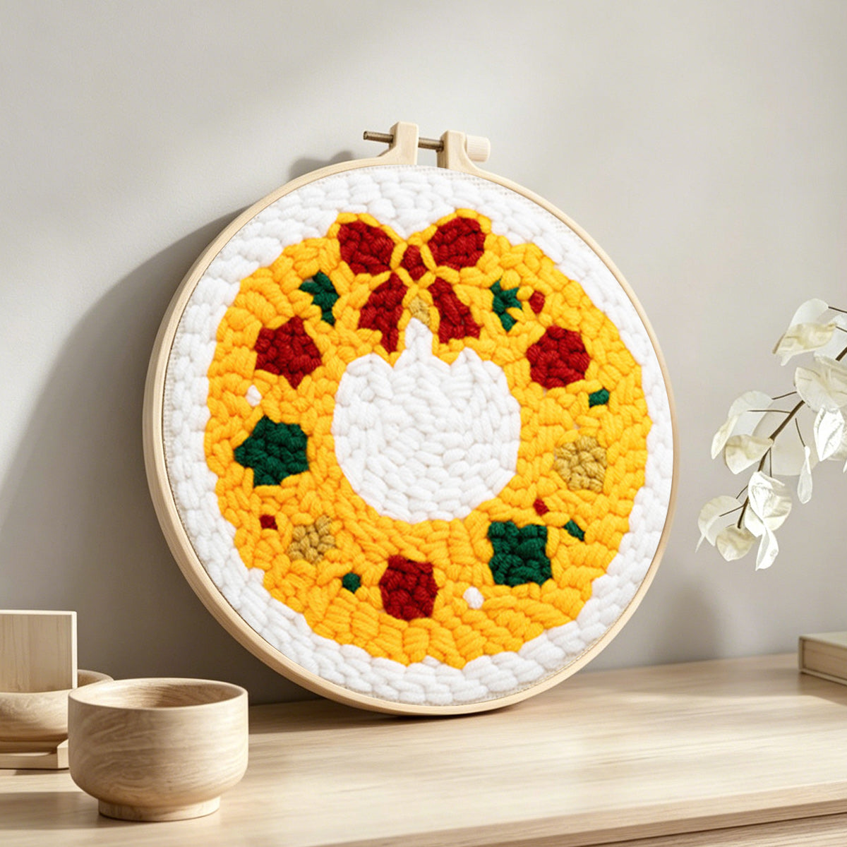 Golden christmas wreath punch needle artwork displayed on a table
