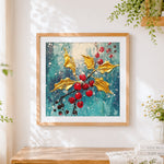 Finished golden holly leaves and red berries cross stitch artwork displayed
