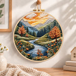 Golden hour mountain river embroidery hoop wall art displayed as warm and cozy handmade home decor