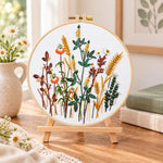 Golden wheat and poppy blooms embroidery kit finished hoop displayed on a wooden stand as cosy tabletop decor