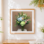 Finished green and blue hydrangea arrangement cross stitch artwork displayed