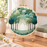 Green forest path embroidery kit finished hoop displayed on a wooden stand as cosy tabletop decor