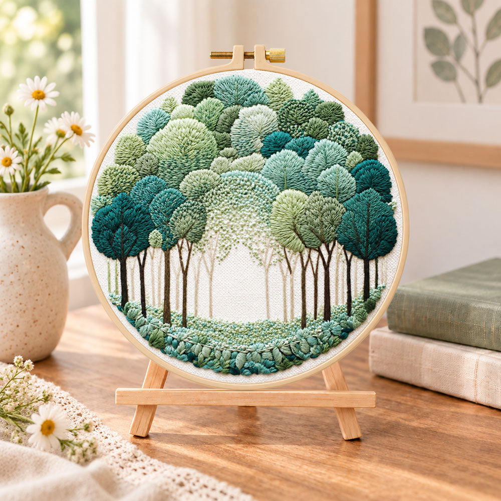 Green forest path embroidery kit finished hoop displayed on a wooden stand as cosy tabletop decor