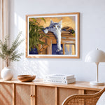 Grey cat lounging on a cabinet cross stitch artwork displayed on wall as home decor