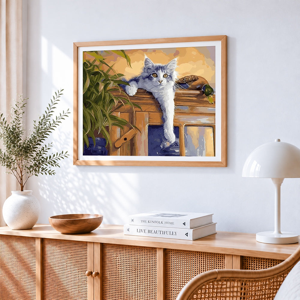 Grey cat lounging on a cabinet cross stitch artwork displayed on wall as home decor