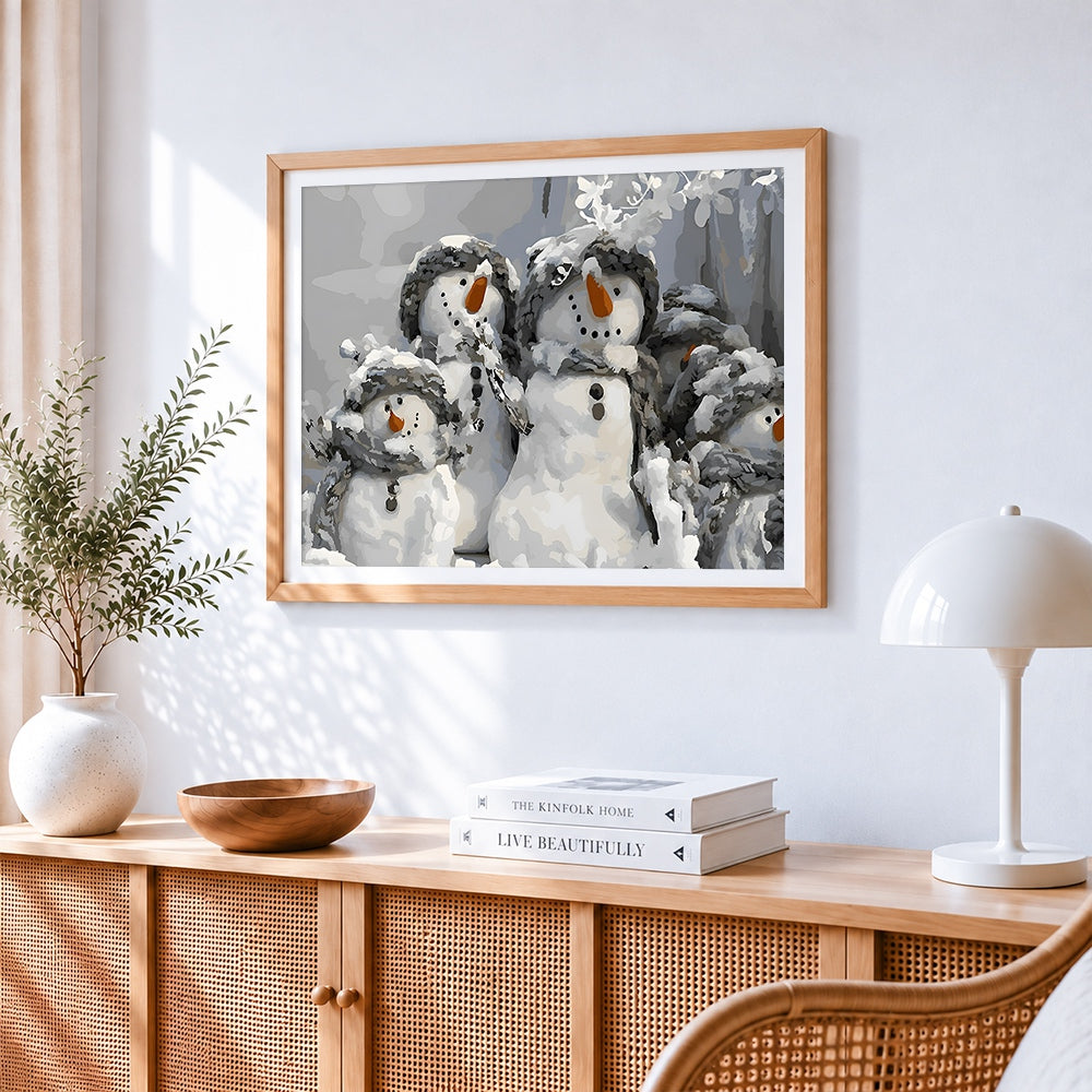Group of snowmen in winter hats cross stitch artwork displayed on wall as home decor