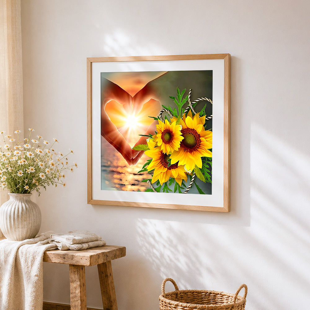 Hands making a heart with sunflowers cross stitch artwork displayed on wall as home decor