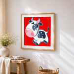 Happy jumping cow cross stitch artwork displayed on wall as home decor
