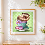 Finished hedgehog in a teacup with macarons cross stitch artwork displayed