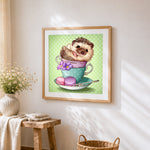 Hedgehog in a teacup with macarons cross stitch artwork displayed on wall as home decor