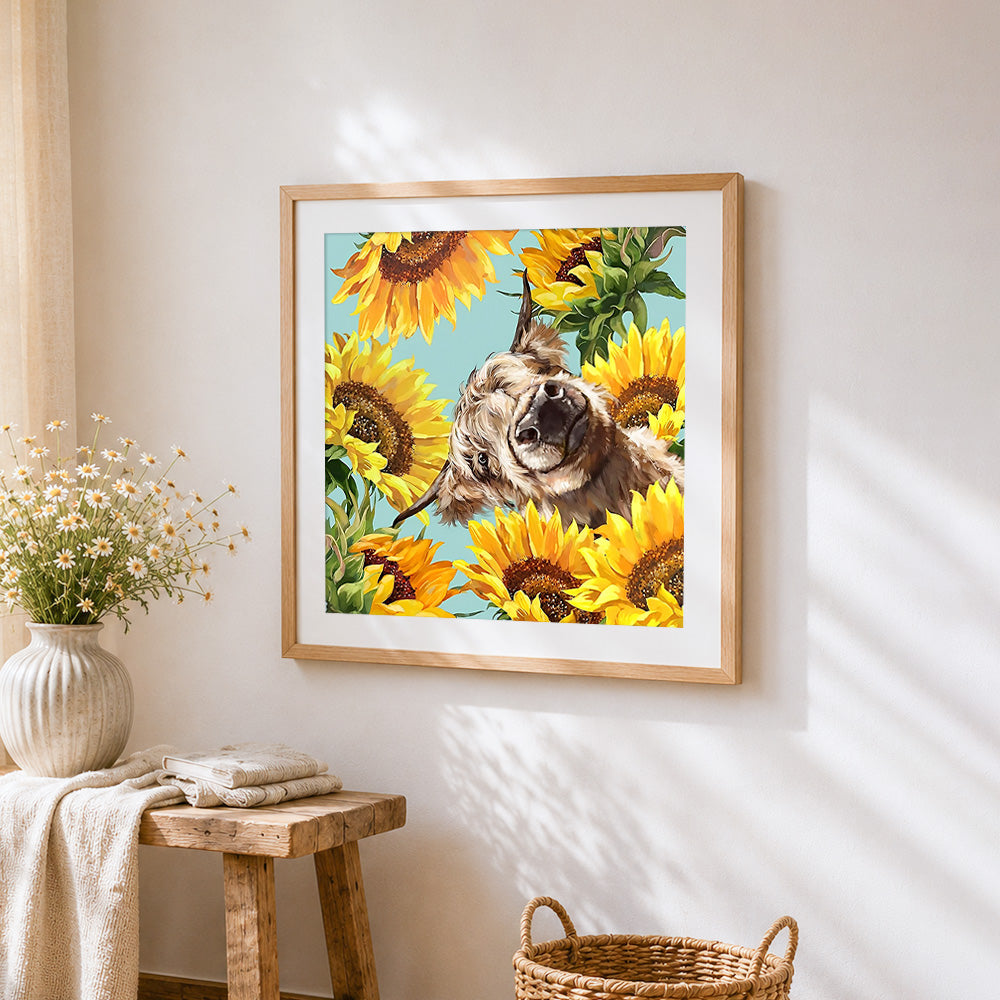 Highland cow surrounded by sunflowers cross stitch artwork displayed on wall as home decor