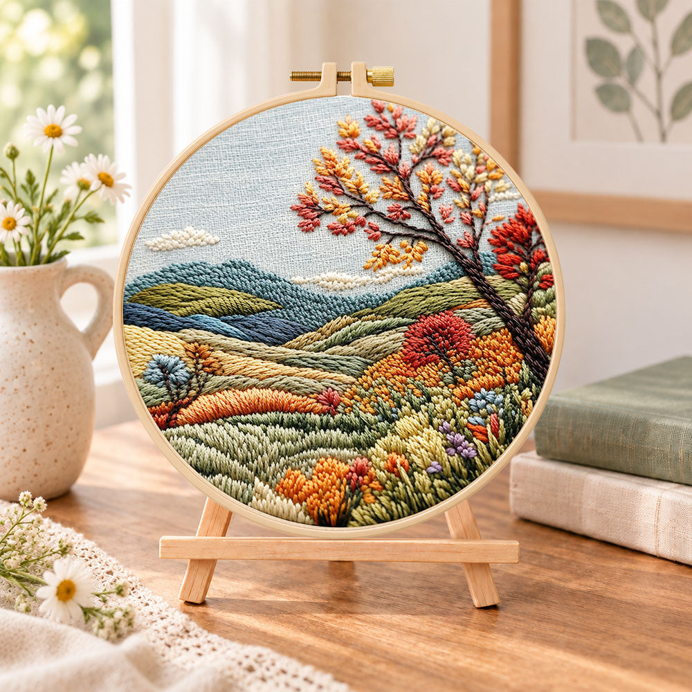 Hillside fall tree view embroidery kit finished hoop displayed on a wooden stand as cozy tabletop decor