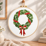 Holly wreath with bow embroidery hoop wall art displayed as warm and cozy handmade home decor